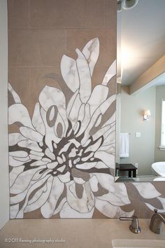 a white flower painted on the side of a wall next to a sink and mirror