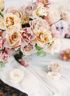 a bouquet of flowers sitting on top of a white cloth covered table with pink and yellow flowers