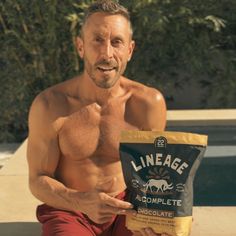 a shirtless man holding a bag of chocolate