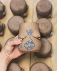 a person holding up a small cup with an image on it in front of some chocolates