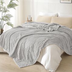 a bed covered in a gray blanket next to a window