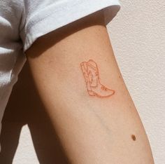 a small red boot tattoo on the left upper arm and right lower arm, which has a line drawing of a cowboy's boot