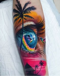 an eye with a rainbow and palm tree on the side of his arm is shown