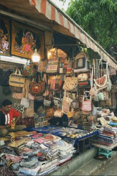 an outdoor market with lots of handbags and purses