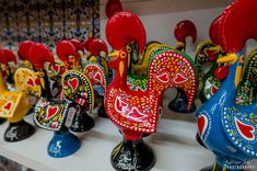 colorful rooster figurines sitting on top of a shelf