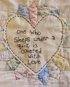 a quilted heart with the words one who sleeps under a quilt is covered with love