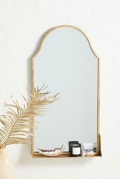 a mirror sitting on top of a wooden shelf next to a potted palm tree