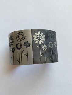 This is a beautiful vintage tattooed steel cuff bracelet. The bracelet name is 50/50 Daisies.  The piece measures 1 1/2" wide It measures 5 1/2 " interior circumference.  It is hallmarked with the Tattooed Steel logo and Patent pending. Made in the USA This item is an excellent preowned vintage condition with normal wear for the age Steel Logo, Bracelet Name, Topaz Yellow, Mom Fall, Chevron Necklace, Solid Gold Bracelet, Peridot Green, Pink Sapphire Ring, Vintage Tattoo