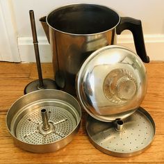 a metal pot and pan sitting on top of a wooden table next to each other