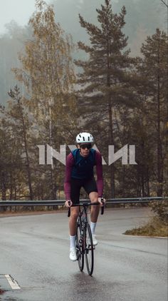 a man riding a bike down the middle of a road with trees in the background