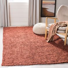 an orange rug in a living room with a white chair and large window behind it