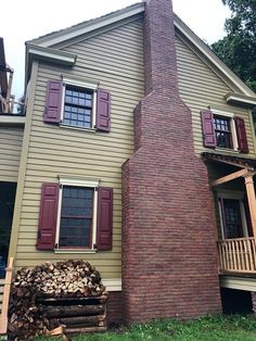 a brick chimney in front of a house with red shutters