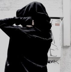 a person wearing a black hoodie standing in front of a wall