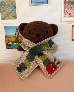 a brown teddy bear sitting on top of a table next to pictures and magnets