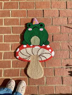 a person standing next to a brick wall with a frog on top of a mushroom