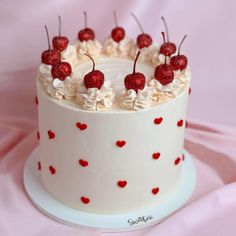 a white cake with red hearts and cherries on top