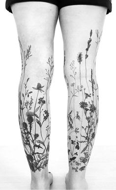 a woman's legs with tattoos on them and flowers all over the leg area