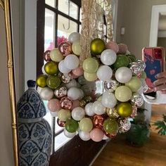 a wreath hanging from the front door with ornaments around it and a person taking a photo