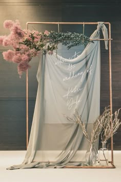 a wedding dress hanging on a clothes rack with flowers and greenery next to it