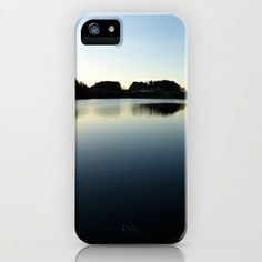 an iphone case with water and trees in the background on a clear day at dusk