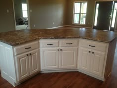 an empty kitchen with white cabinets and granite counter tops in the middle of the room