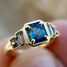 a close up of a person holding a gold ring with blue and white stones on it