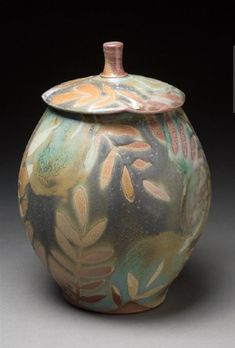 a ceramic jar with leaves painted on it