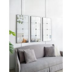 three mirrors are hanging on the wall above a couch in a living room with white walls