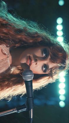 a woman with long hair holding a microphone