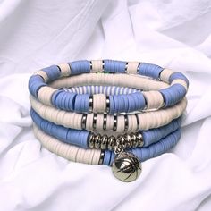 Show your team pride with our set of 4 light blue and white game day stackable bracelets. Each handmade bracelet is made from polymer clay heishi discs on stretch beading thread and finished with silver charm.  Chose from a selection of mascot and sport charms to finish off the stack To get the best fit for your bracelet, we recommend measuring your wrist and then adding 1/2". Bead Bracelet Stack, Heishi Bead Bracelet, Beaufort Nc, Beading Thread, Stackable Bracelets, Heishi Beads, Handmade Bracelet, Bracelet Stack, Team Colors