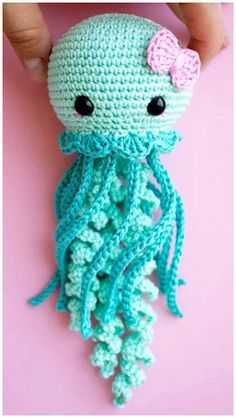 a crocheted octopus with a pink bow on it's head is being held by someone