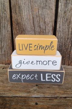 three stacked wooden blocks that say live simple, give more expect less