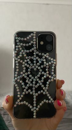 a woman is holding up her phone case with beads on the front and back of it