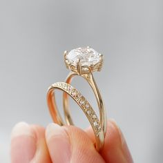 a person holding an engagement ring with a diamond in it's center and side stones on the band