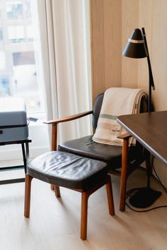 a chair and ottoman in front of a desk with a lamp on top of it