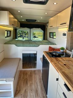 the interior of an rv with wood flooring and white cabinets, including a kitchen area