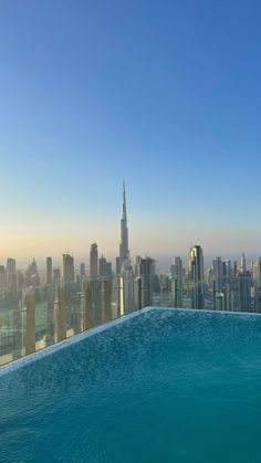 an empty swimming pool in front of a large cityscape with skyscrapers on the horizon