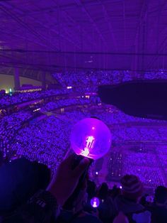 a person holding up a purple light in the middle of a large room filled with people