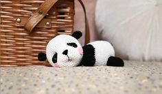 a stuffed panda bear laying on top of a bed next to a wicker basket