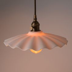 a white light hanging from a ceiling fixture with an orange light on the top and bottom