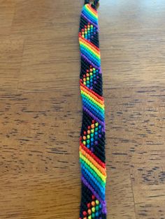 a multicolored beaded tie on a wooden table with a black string attached to it