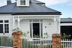 a white house with a black roof and gate