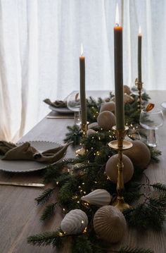 a long table with candles, plates and napkins on it is decorated for christmas