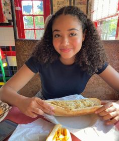 a woman sitting at a table with a sandwich in front of her