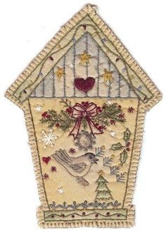 an embroidered house with a bird on the front and christmas decorations in the bottom corner