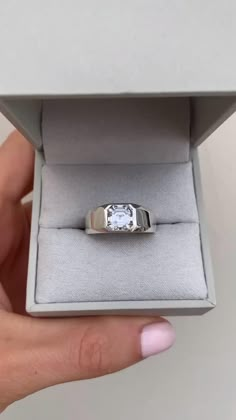 a person is holding an engagement ring in their hand and it has a white diamond on the side