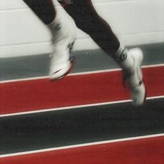 a close up of a person's legs and feet in white shoes on a track