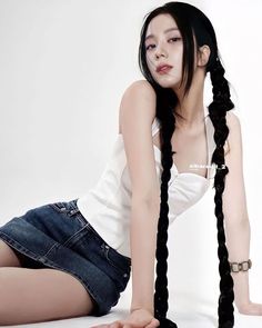 a woman with long black hair sitting on the ground