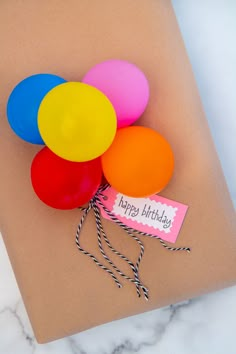 a bunch of balloons tied to a piece of brown paper with a tag on it