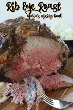 a piece of meat sitting on top of a wooden cutting board next to a fork